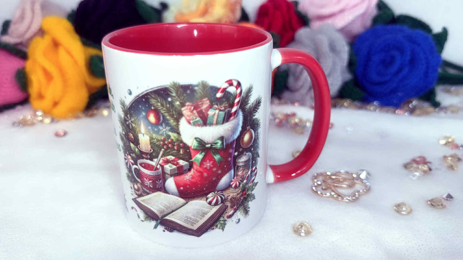 Decorative Christmas-themed mug with a red interior and handle, surrounded by colorful flowers and decorative items.