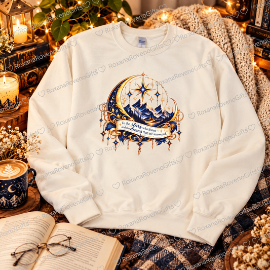 Front of a white Night Court-inspired bookish sweatshirt featuring blue and gold mountains, crescent moon, stars and the To the Stars Who Listen quote, by RoxanaRovenoGifts.