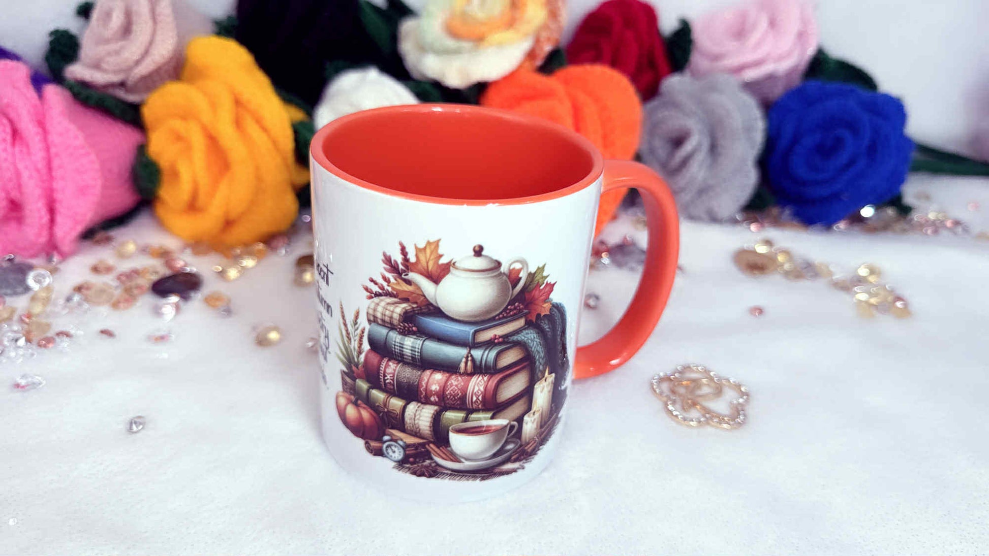 Mug with a colorful design of books and a teapot on a white surface with decorative flowers in the background. The ideal autumn gift: a cosy mug that makes every drink a seasonal treat - personalised gifts by Roxana Roveno, perdect gift for autumn book lover - irl dreaming
