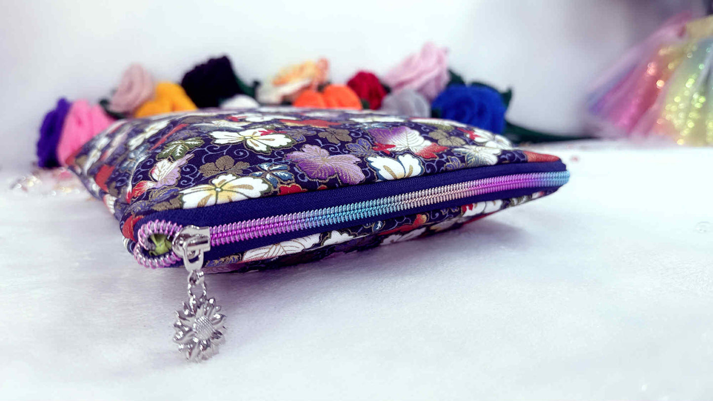 Floral-patterned pouch with tassels on a white background. Handmade book sleeve by Roxana Roveno