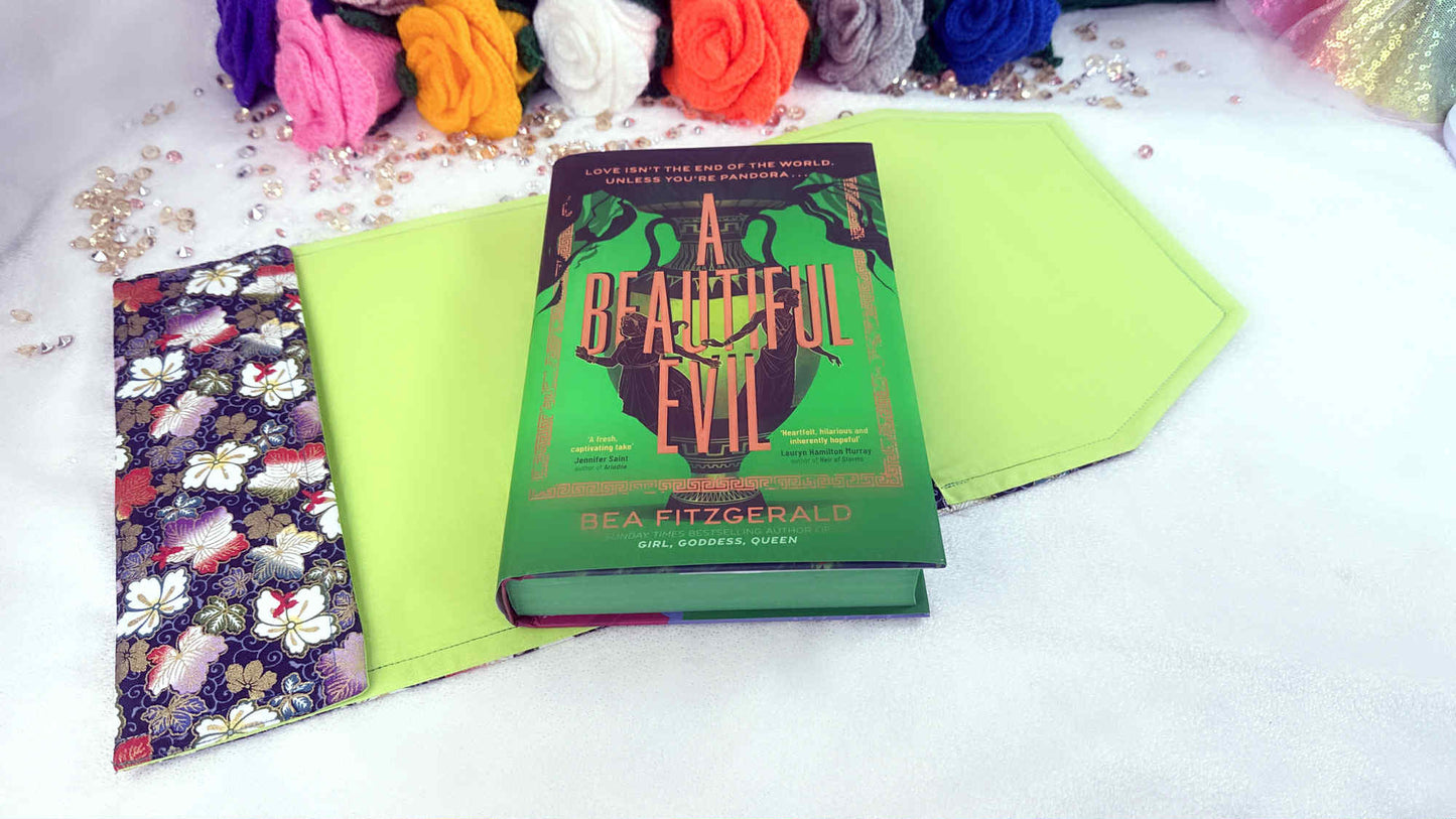 Book titled 'A Beautiful Evil' by Sea Fitzgerald on a white surface with colorful flowers in the background. Handmade book cover by Roxana Roveno